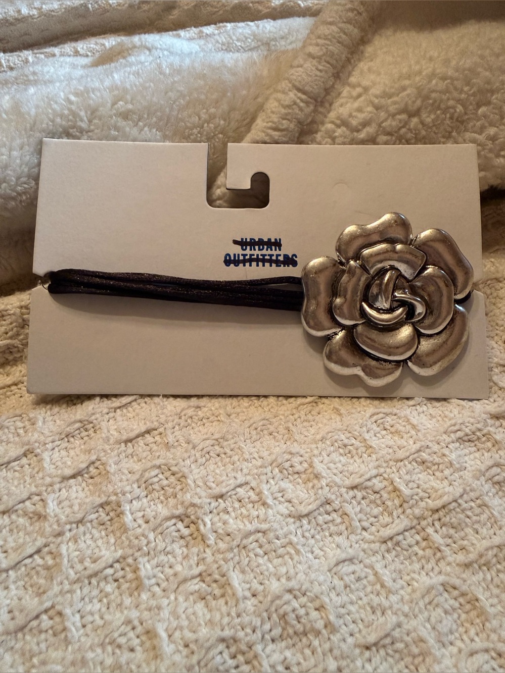 Urban Outfitters silver metal rose flower hair tie on a black cord.